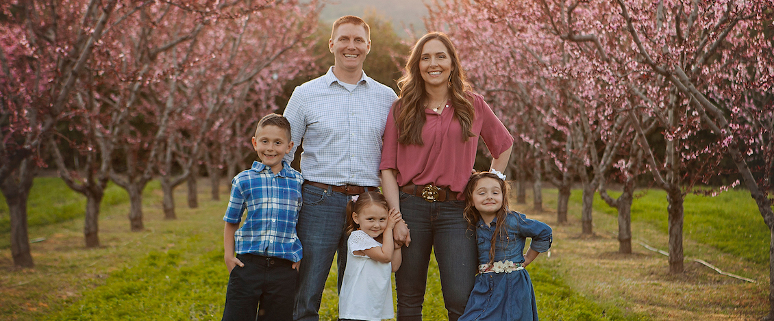 Lisa and Cliff Howard standing with their children in an orchard